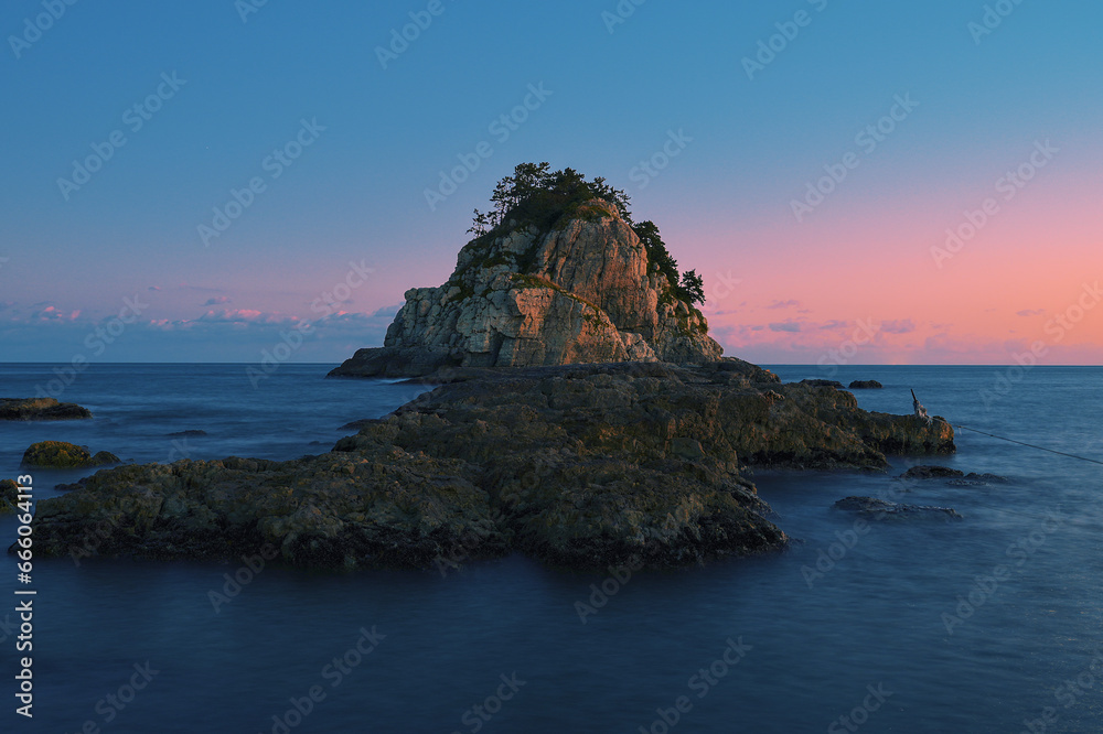A small rocky island illuminated by the setting sun A small rocky island illuminated by the setting sun