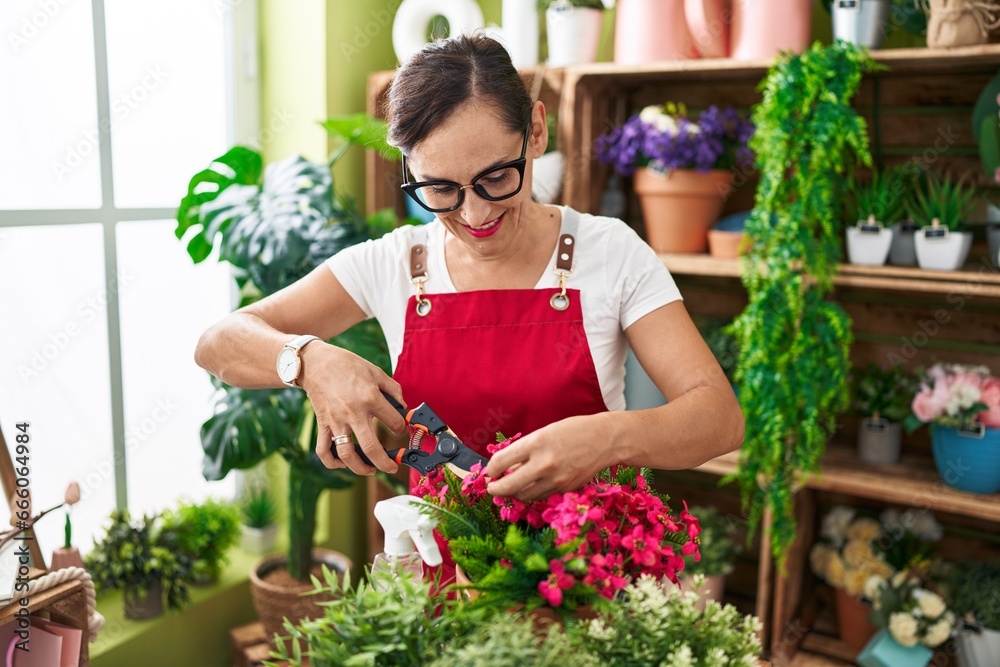 Young beautiful hispanic woman florist cutting plants at flower shop