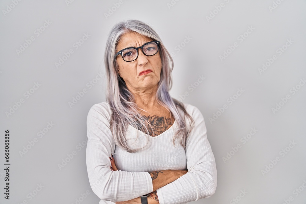 Middle age woman with grey hair standing over white background skeptic and nervous, disapproving expression on face with crossed arms. negative person. Middle age woman with grey hair standing over white background skeptic and nervous, disapproving expression on face with crossed arms. negative person.