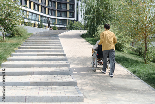 Rear view of young man walking with his friend with disability in the city