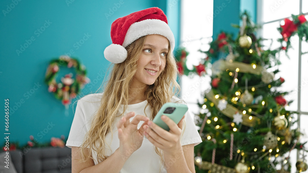 Young blonde woman using smartphone celebrating christmas at home Young blonde woman using smartphone celebrating christmas at home