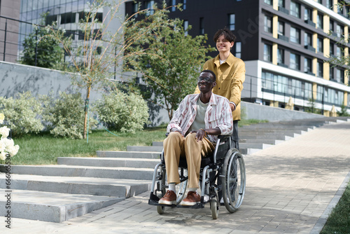 Guy walking with his friend with disability along the street