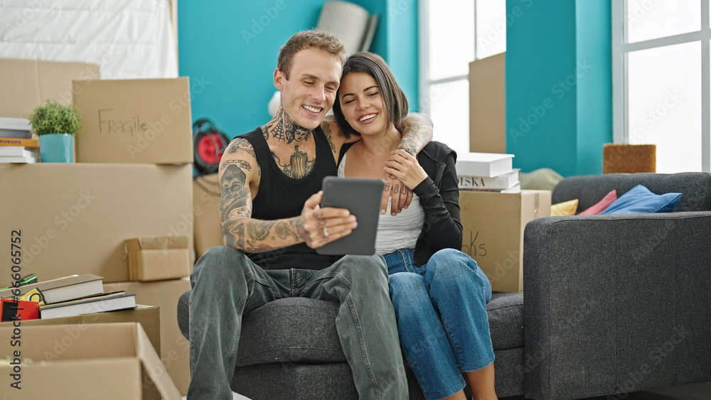 Beautiful couple hugging each other using touchpad smiling at new home Beautiful couple hugging each other using touchpad smiling at new home