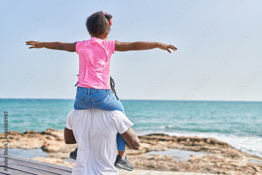 Father and daughter holding girl on shoulders standing on back view at seaside Father and daughter holding girl on shoulders standing on back view at seaside