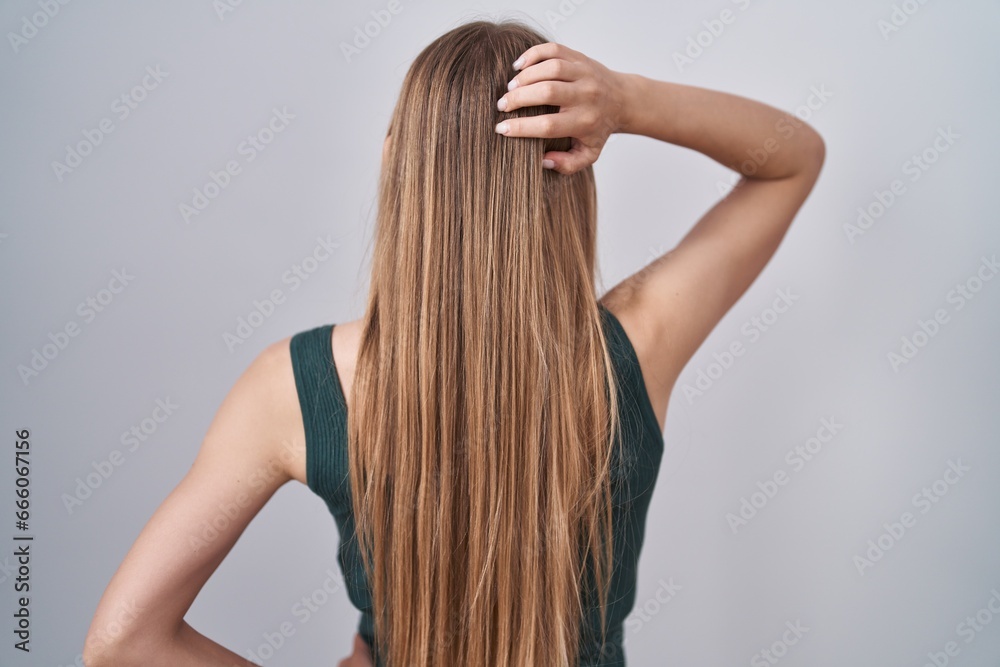 Young caucasian woman standing over white background backwards thinking about doubt with hand on head Young caucasian woman standing over white background backwards thinking about doubt with hand on head