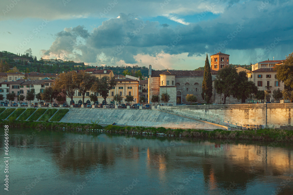 Fair Verona concept. A view to Adige river and Passeggiata di San Giorgio from Ponte Pietra in the old city centre. Dramatic cloudy sky. Outdoor shot