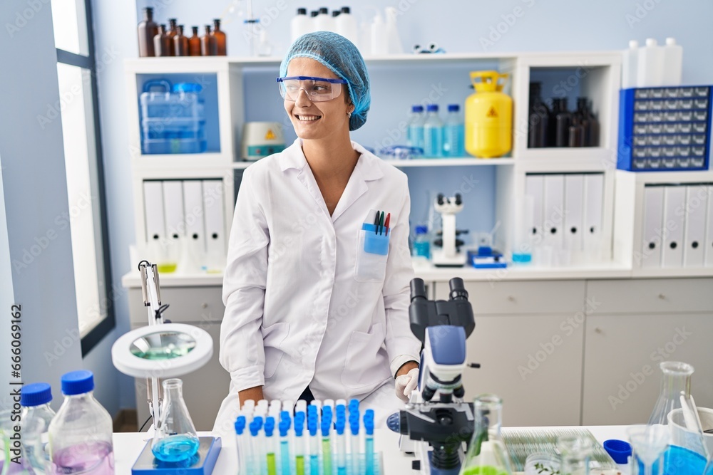 Brunette woman working at scientist laboratory looking away to side with smile on face, natural expression. laughing confident. Brunette woman working at scientist laboratory looking away to side with smile on face, natural expression. laughing confident.