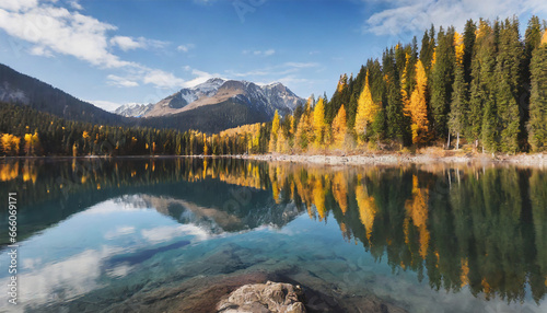 Autumn woods mirrored in a lake. Vibrant autumn sunrise in the mountainous terrain. Scenic morning at a mountain lake. Fall season in Canada