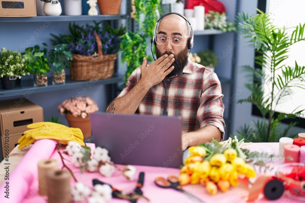 Young hispanic man with beard and tattoos working at florist shop doing video call covering mouth with hand, shocked and afraid for mistake. surprised expression Young hispanic man with beard and tattoos working at florist shop doing video call covering mouth with hand, shocked and afraid for mistake. surprised expression