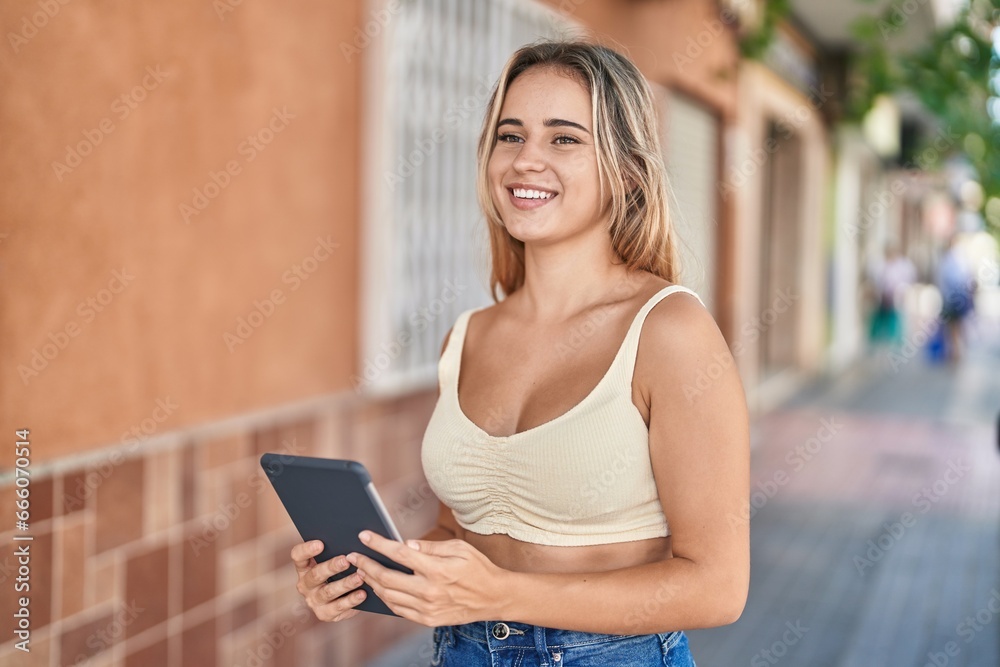 Obraz premium Young blonde woman smiling confident using touchpad at street