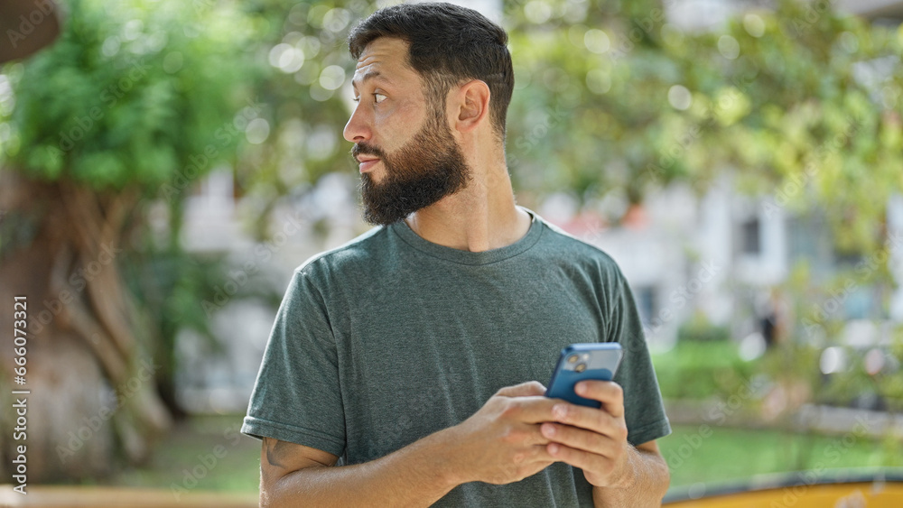 Young hispanic man using smartphone with serious expression at park Young hispanic man using smartphone with serious expression at park