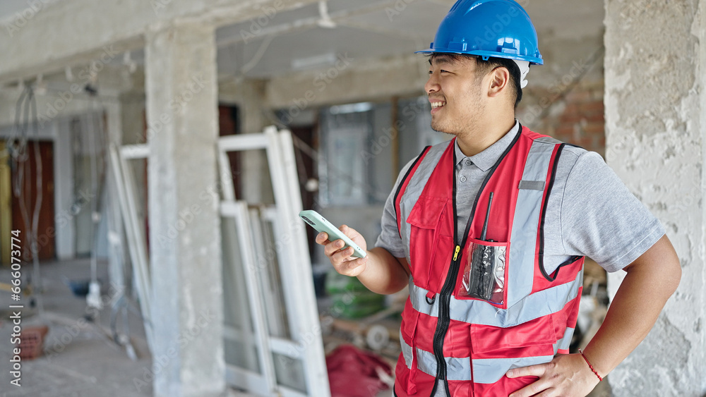 builder using smartphone smiling at construction site builder using smartphone smiling at construction site