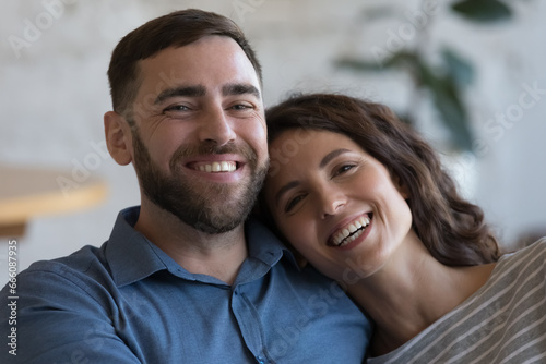 Happy attractive adult couple in love indoor head shot close up portrait. Cheerful husband and wife hugging with love, affection at home, looking at camera, smiling, laughing © fizkes