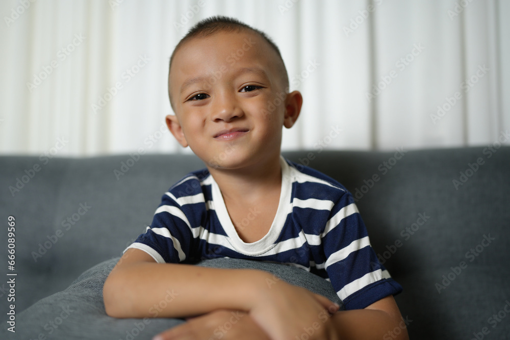 Happy smiling Asian boy on the sofa inside the house. Happy smiling Asian boy on the sofa inside the house.
