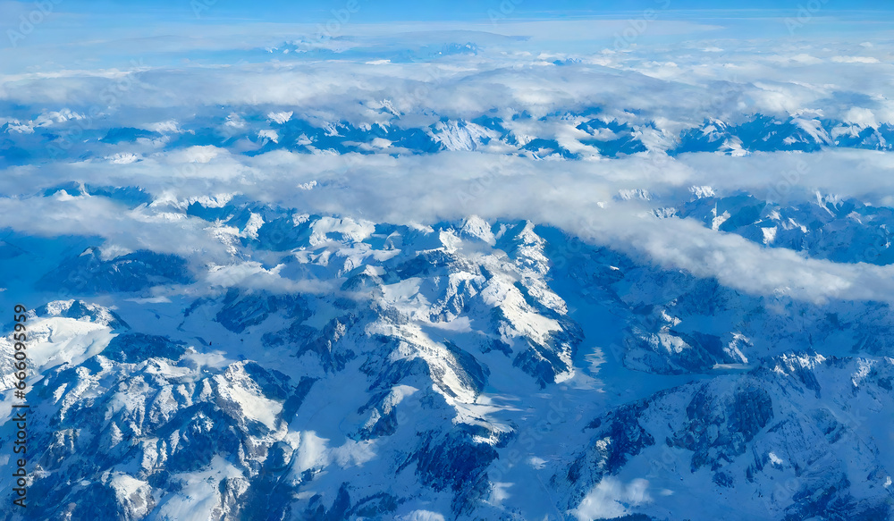 Aerial view of Alps mountain range with snow and blue sky.