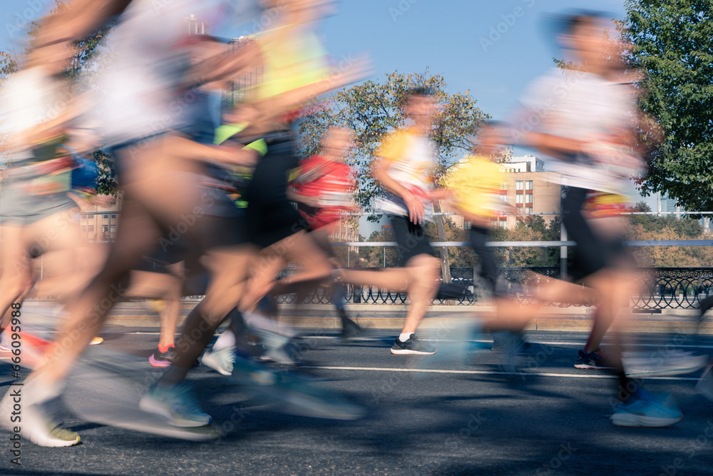 Fototapeta premium Blurred silhouettes of athletes running marathon on street of big city showing speed and endurance