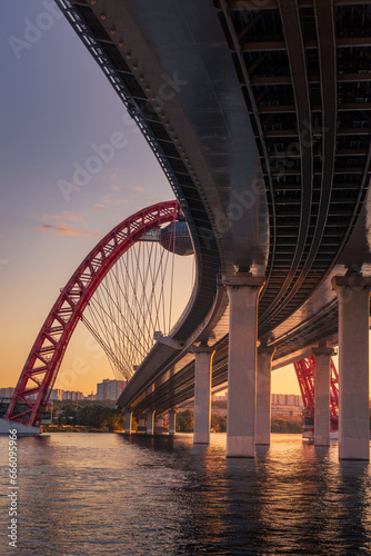 Photography Sunset cityscape with modern arched cable stayed bridge reflecting in river wate