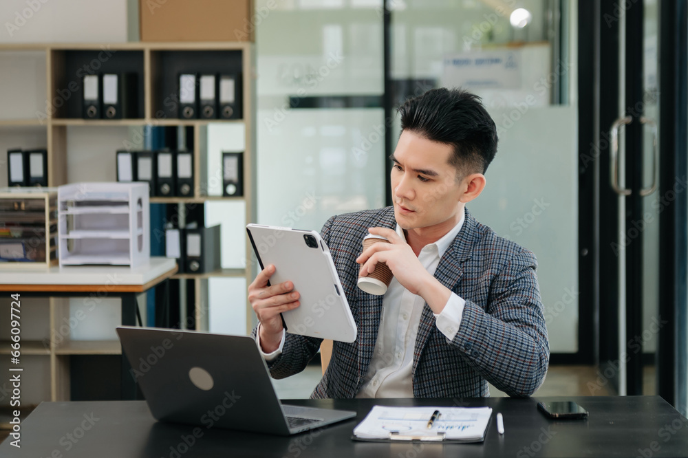 Confident Asian man with a smile standing holding notepad and tablet at the modern office. Confident Asian man with a smile standing holding notepad and tablet at the modern office.
