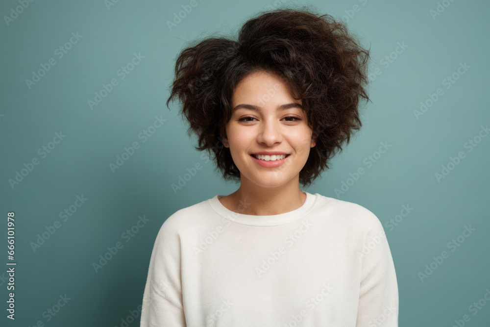 Everyday people. A smiling woman. Brown curly hair to her shoulders. Hair with volume.  Wearing a white shirt. On a light studio background. Portrait.