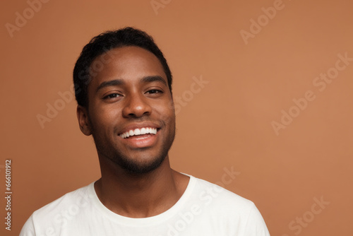 Everyday people. A smiling handsome African American man. Wearing a white t-shirt. On a light background. Friendly man. Down-to-earth and approachable. Portrait.