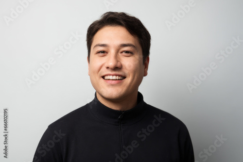 An smiling asian man wearing a black jumper. On a white studio background. Portrait.