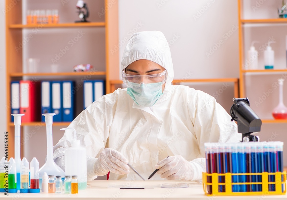 Young biochemist wearing protective suit working in the lab Young biochemist wearing protective suit working in the lab