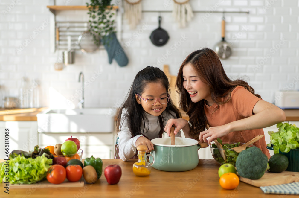 Portrait of enjoy happy love asian family mother with little asian girl daughter child help cooking food healthy eat with fresh vegetable testing smell soup in a pot with spoon.helping mommy. Portrait of enjoy happy love asian family mother with little asian girl daughter child help cooking food healthy eat with fresh vegetable testing smell soup in a pot with spoon.helping mommy.