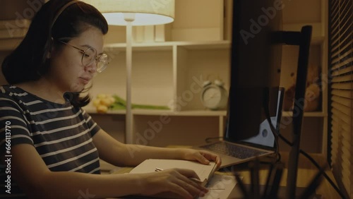 Young female student reading a book on the desk, Doing homework in the middle of the night, Self study, Textbooks from books, Find out more, Study concept.