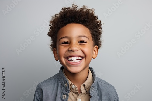 A professional portrait studio photograph featuring an adorable, mixed-race young boy with immaculately clean teeth, radiating joy with laughter and smiles. This image is isolated on white background