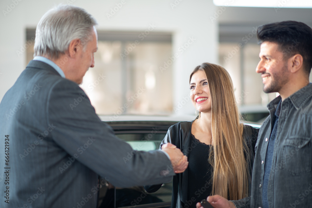 Man giving an handshake and giving keys to seal the deal for new car Man giving an handshake and giving keys to seal the deal for new car
