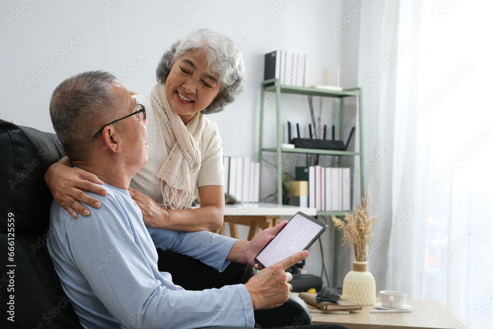 senior couple sitting on sofa using tablet while video call online with family in living room at home senior couple sitting on sofa using tablet while video call online with family in living room at home
