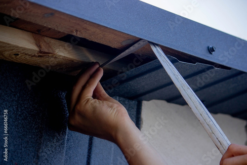a man repairs the roof, tightens the self-tapping screw with a screwdriver