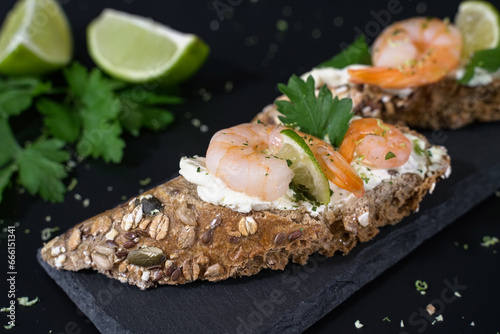 Closeup Crispy appetizer with wholemeal bread, spreadable cheese, shrimp and lime