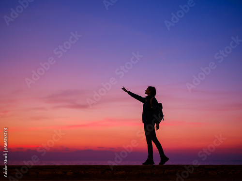 Woman tourist against sunset sky