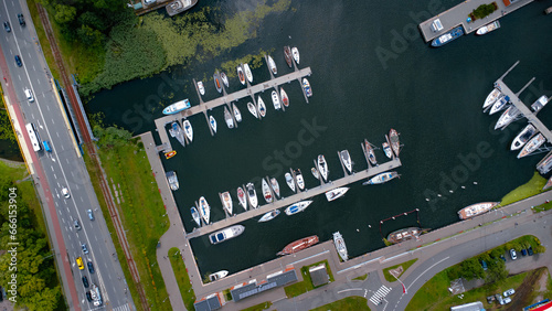 A beautiful harbour with several boats and sailboats parked symmetrically in the Polish town of Kolobrzeg. Taken from a drone from a bird's eye view. Top down seaport traffic 
