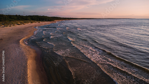 Sea waves at sunset on the Baltic Sea. A sandy beach in Kolobřeh. Taken from a drone. Kołobrzeg is city in Poland. Top down