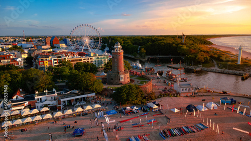 Kolobrzeg town at sunset. Ferris wheel, lighthouse, harbour and sandy beach. Taken from a drone. Kołobrzeg is a city in Poland.