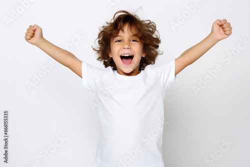 Mockup T-Shirt  - Kind freut sich und reißt die Arme hoch. Weißer Hintergrund und weißes T-Shirt mit fröhlichem Kleinkind im Studio.  photo