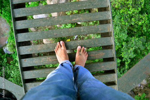 First person view of bare foot at metal bridge at adventure location photo