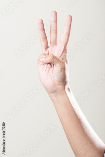 Hand showing three gesture isolated on grey background