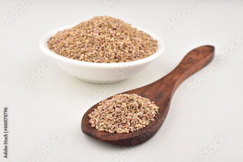 Closeup of carom seeds in spoon and bowl on white background