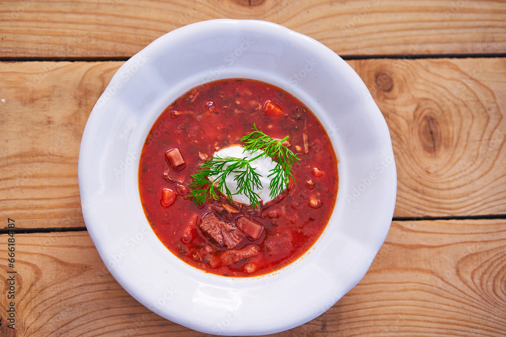 Top view on the rustic style white porcelain deep plate with ukrainian borsch soup. Traditional, delicious and satisfying dish served often like main course for lunch in the eastern european cuisine. Top view on the rustic style white porcelain deep plate with ukrainian borsch soup. Traditional, delicious and satisfying dish served often like main course for lunch in the eastern european cuisine.