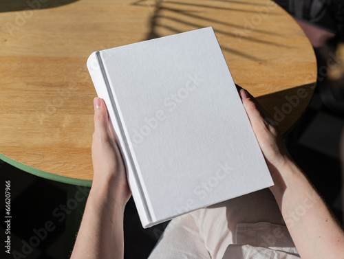 Canvas Print Book cover mockup, hand holding blank clean hardcover mock up on wood desk
