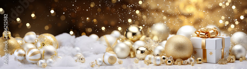 Christmas atmosphere, on a horizontal surface against a background of golden bokeh lie festive New Year decorations, balls and a gift around snow in white and gold tones. Christmas banner.