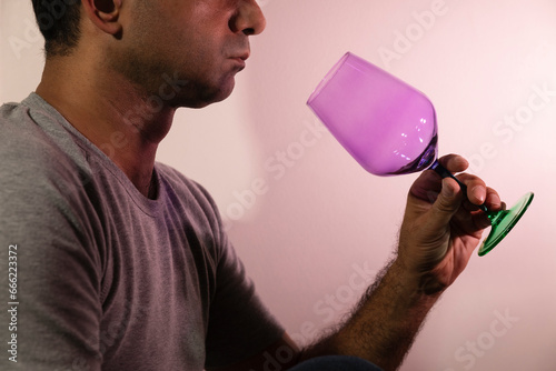 Unrecognizable caucasian man holding an empty wineglass looking inside in profile portrait shot.