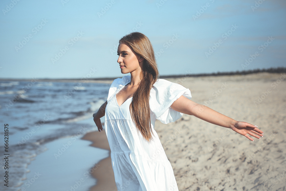 Happy smiling beautiful woman is on the ocean beach in a white summer dress, open arms Happy smiling beautiful woman is on the ocean beach in a white summer dress, open arms