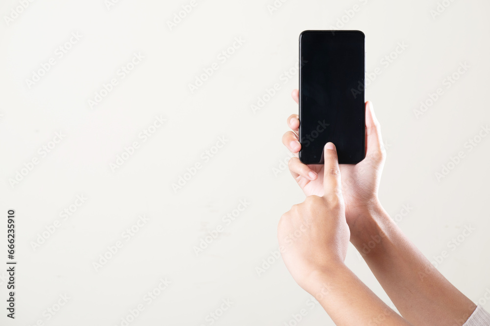 Hand holding smartphone using with finger on grey background