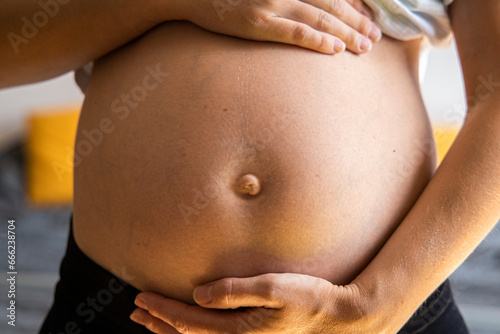 Pregnant young woman listening to baby holding her belly
