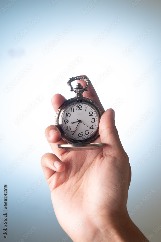 Closeup of pocket watch in hand on grey background Closeup of pocket watch in hand on grey background
