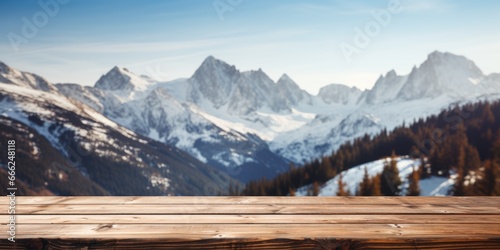 Enjoy the view from a dark wood table on a mountain cabin deck, where a snow-covered forest, icy lake, and towering peaks await.